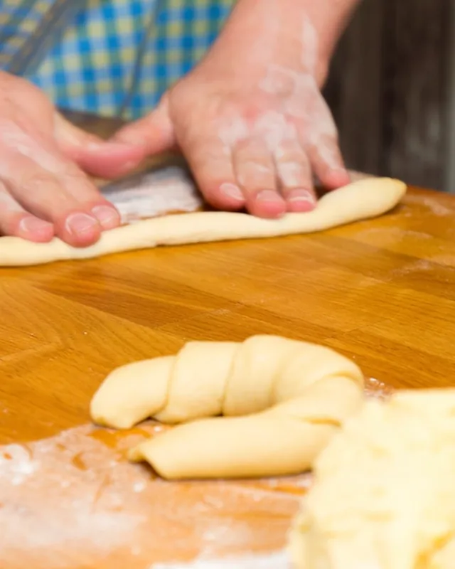 Mains d’un boulanger façonnant de la pâte sur un plan de travail.